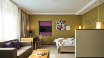 Una habitación de hotel con sofá, cama, escritorio y televisor.