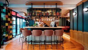 A modern bar area with a central bar counter, four bar stools, and a variety of glassware and jars on the shelves. - Henriette Stadthotel Vienna (Vienna)