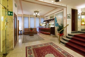 A hotel lobby with a bar, a sofa, a staircase, and a carpeted floor. - Hotel Terminus & Plaza (Pisa)