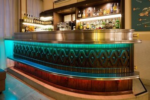 A bar area with a counter, shelves of bottles, and a decorative wall. - Hotel Terminus & Plaza (Pisa)