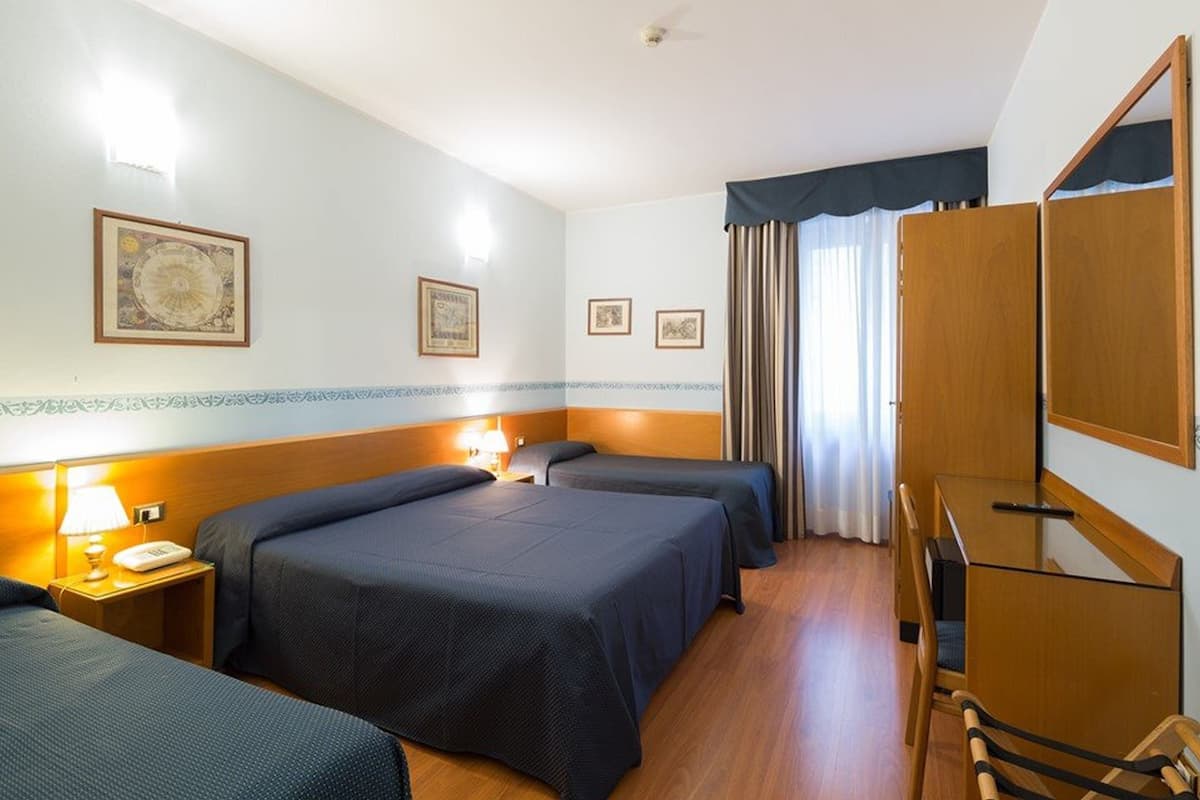 Ein Hotelzimmer mit zwei Betten, einem Schreibtisch, einem Stuhl und einem Kleiderschrank.