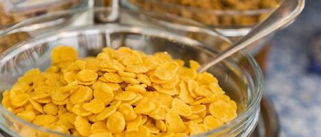 A glass bowl filled with yellow cereal flakes.