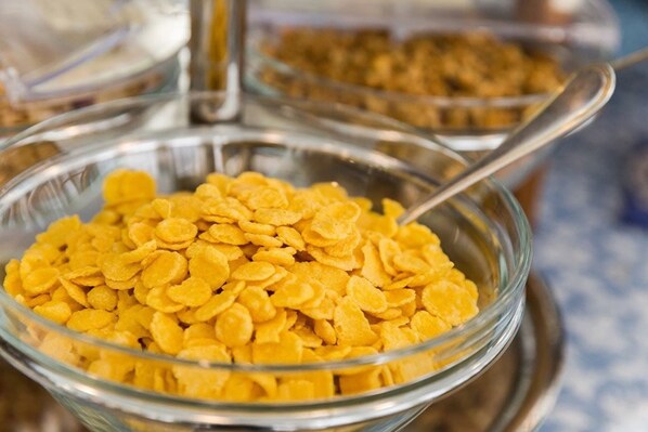 A glass bowl filled with yellow cereal flakes. - Hotel Terminus & Plaza (Pisa)