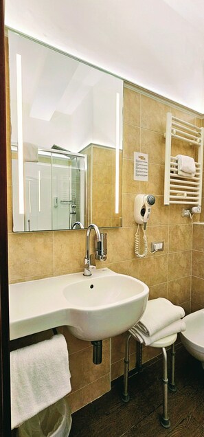 A bathroom with a sink, mirror, towel rack, and a hairdryer. - Hotel Terminus & Plaza (Pisa)