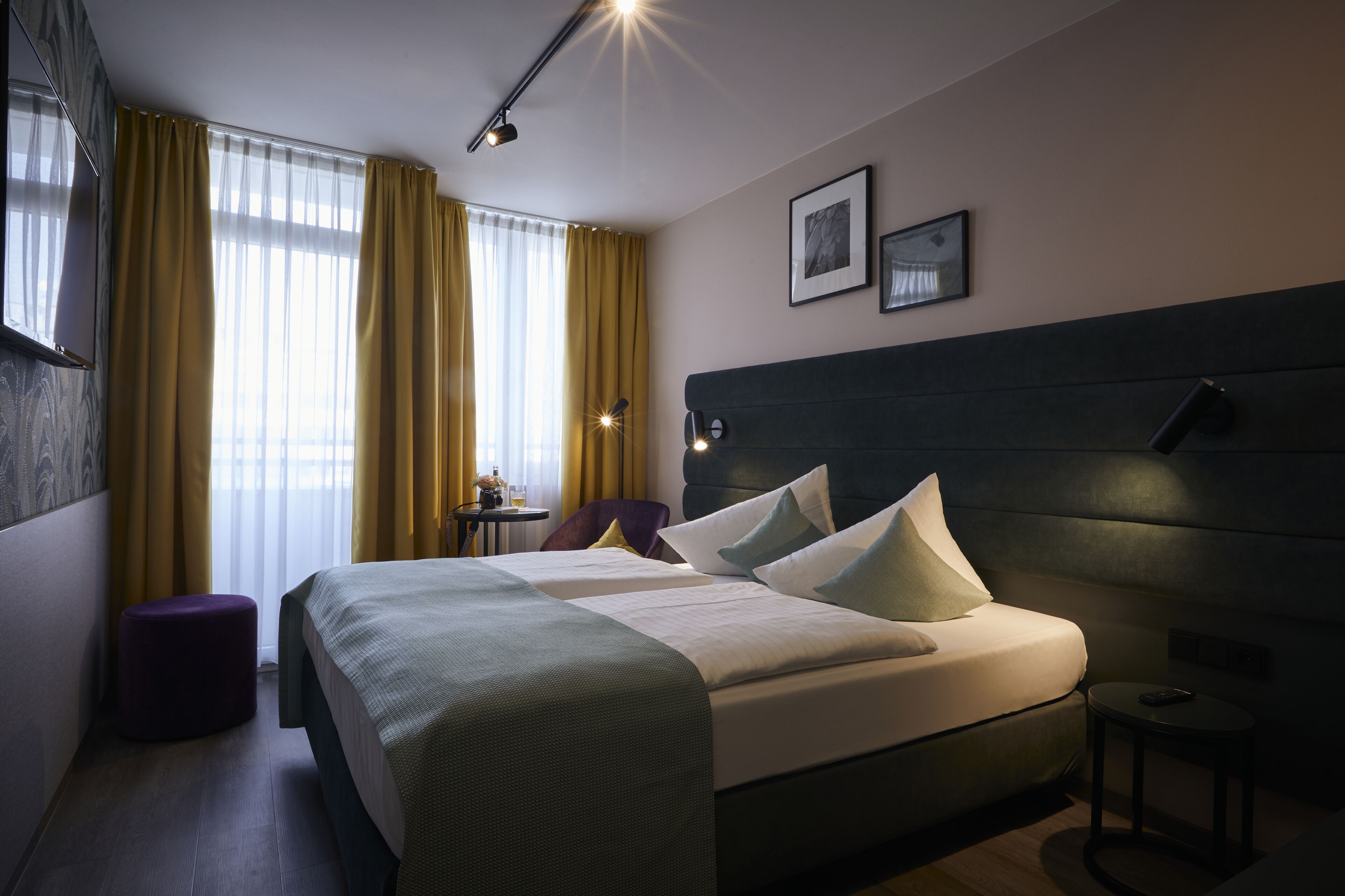 Ein modernes Hotelzimmer mit einem großen Bett, einem kleinen runden Tisch und einem Sessel.