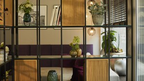 Un salon moderne doté d’une cloison en verre, de panneaux en bois et de différentes plantes.