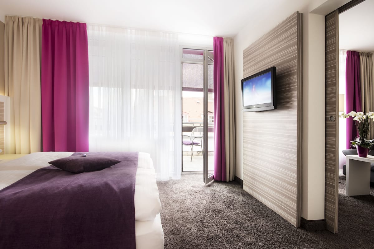 Una camera d'albergo con un letto, una televisione, una scrivania e vista all'esterno.