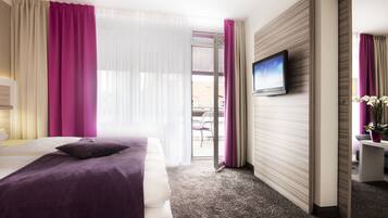Una habitación de hotel con una cama, televisión, escritorio y vistas al exterior.