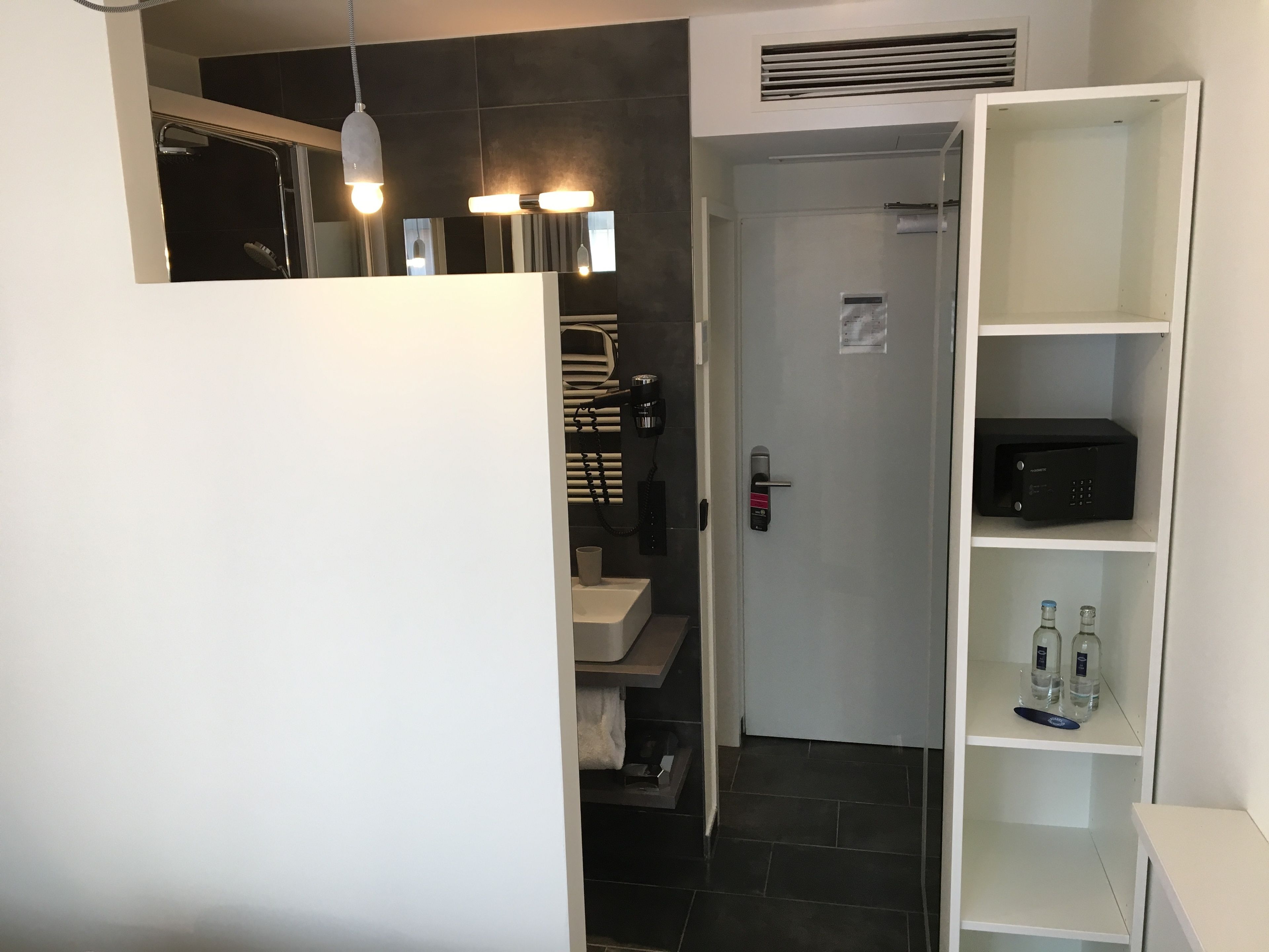 A modern bathroom with a shower, a toilet, a sink, and a built-in cabinet with toiletries.