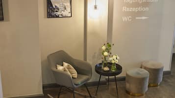 Zona de recepción con mostrador, una silla y señalización en la pared que indica el camino a la recepción y los baños.