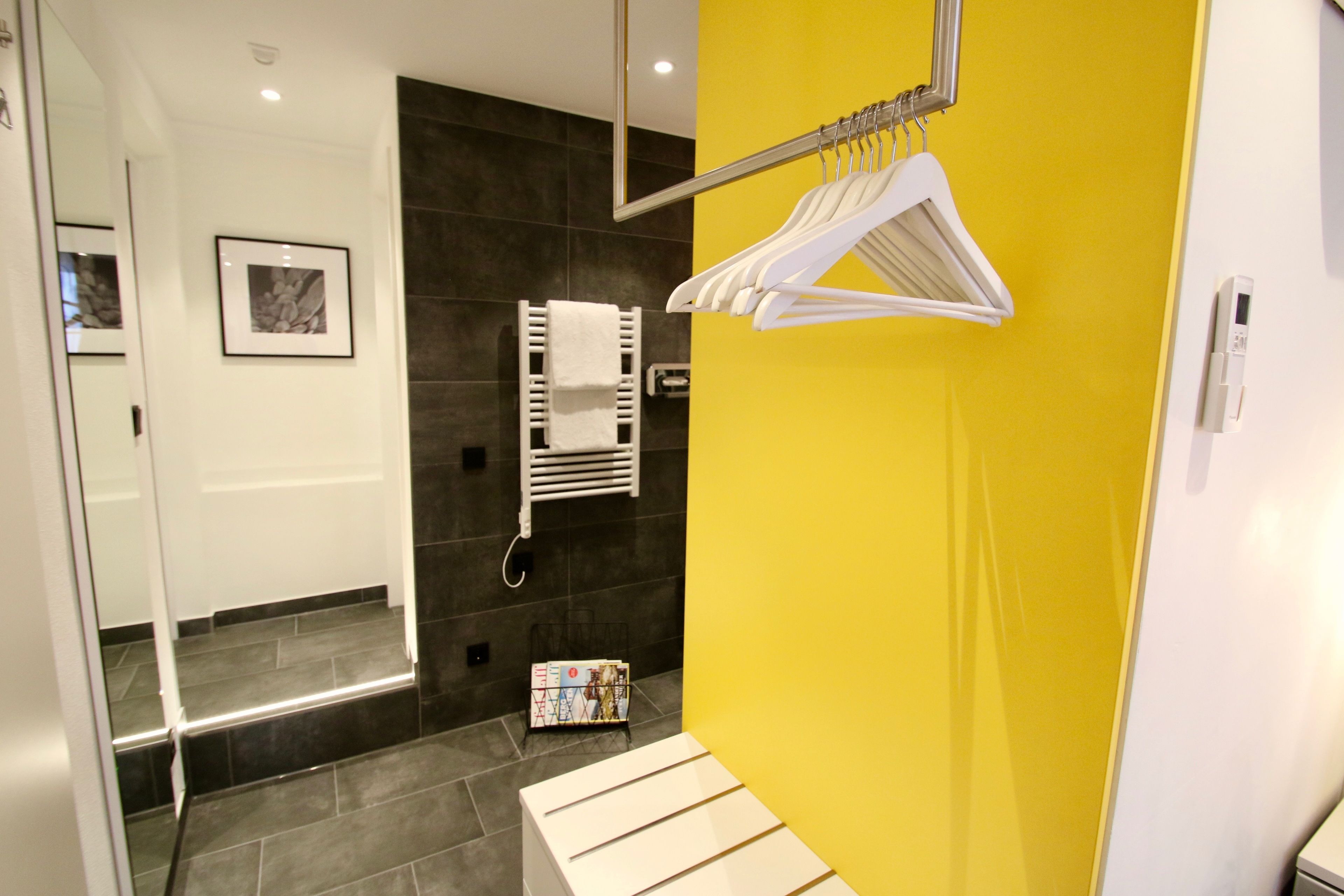 A modern bathroom with a yellow accent wall, a white towel rack, and a framed picture on the wall.