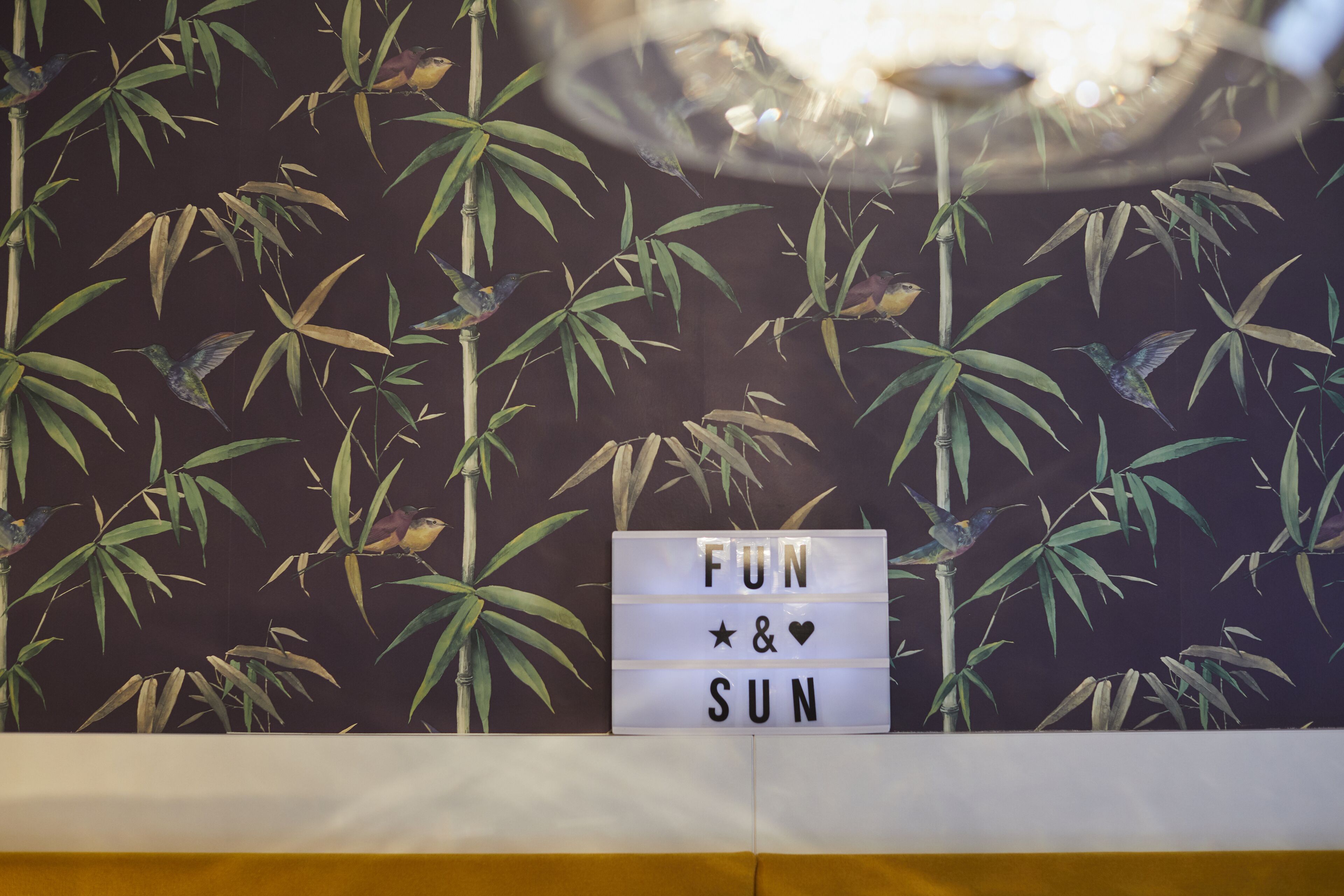 A wall with bamboo plants and a sign that reads "FUN & SUN".