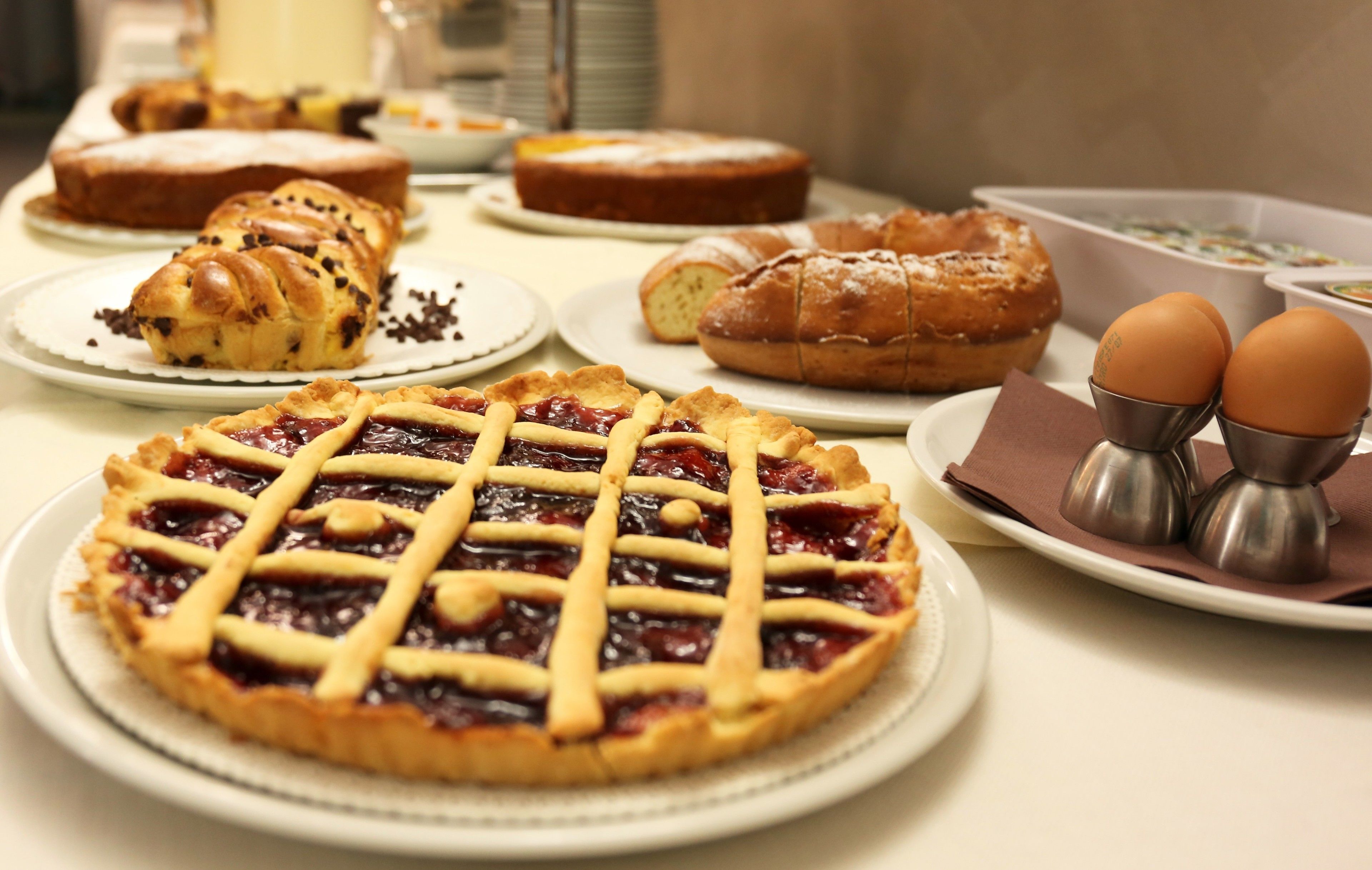 Une variété de produits de boulangerie, notamment une tarte aux cerises, des croissants et une miche de pain, sont disposés sur une table.