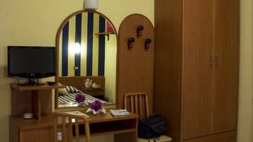 Une chambre à coucher comprenant un lit, un bureau avec une chaise, une télévision, une armoire et un miroir.