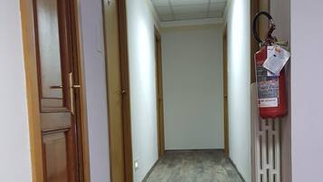 A hallway with wooden doors, a fire extinguisher, and a ceiling light.