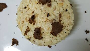 Un plato blanco con arroz en montón y trozos de carne esparcidos.