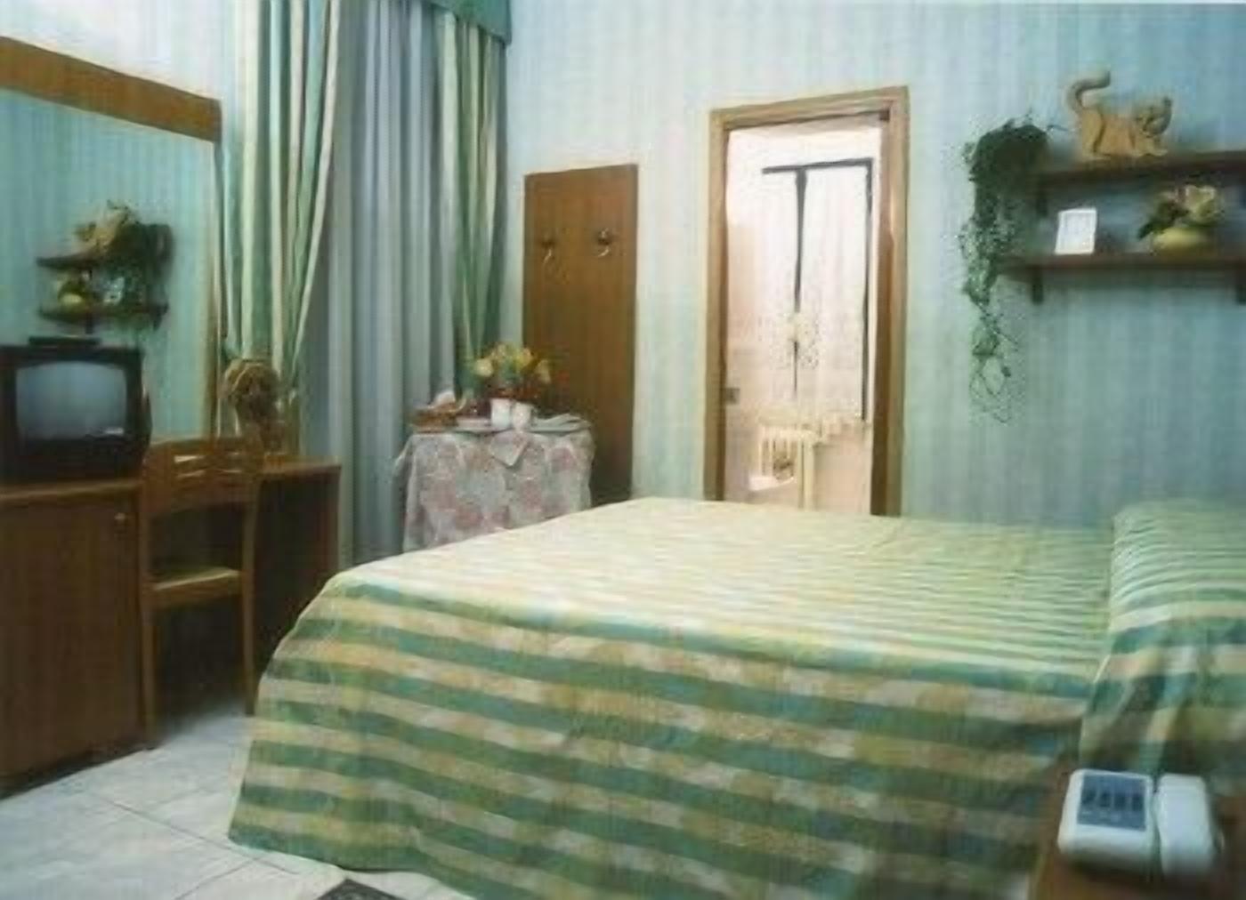 Ein Zimmer mit einem Bett, einem Schreibtisch, einem Stuhl, einem Fernseher und einer Tür.
