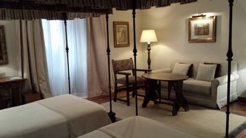 A four-poster bed, a sofa, a table, and a chair in a hotel room.