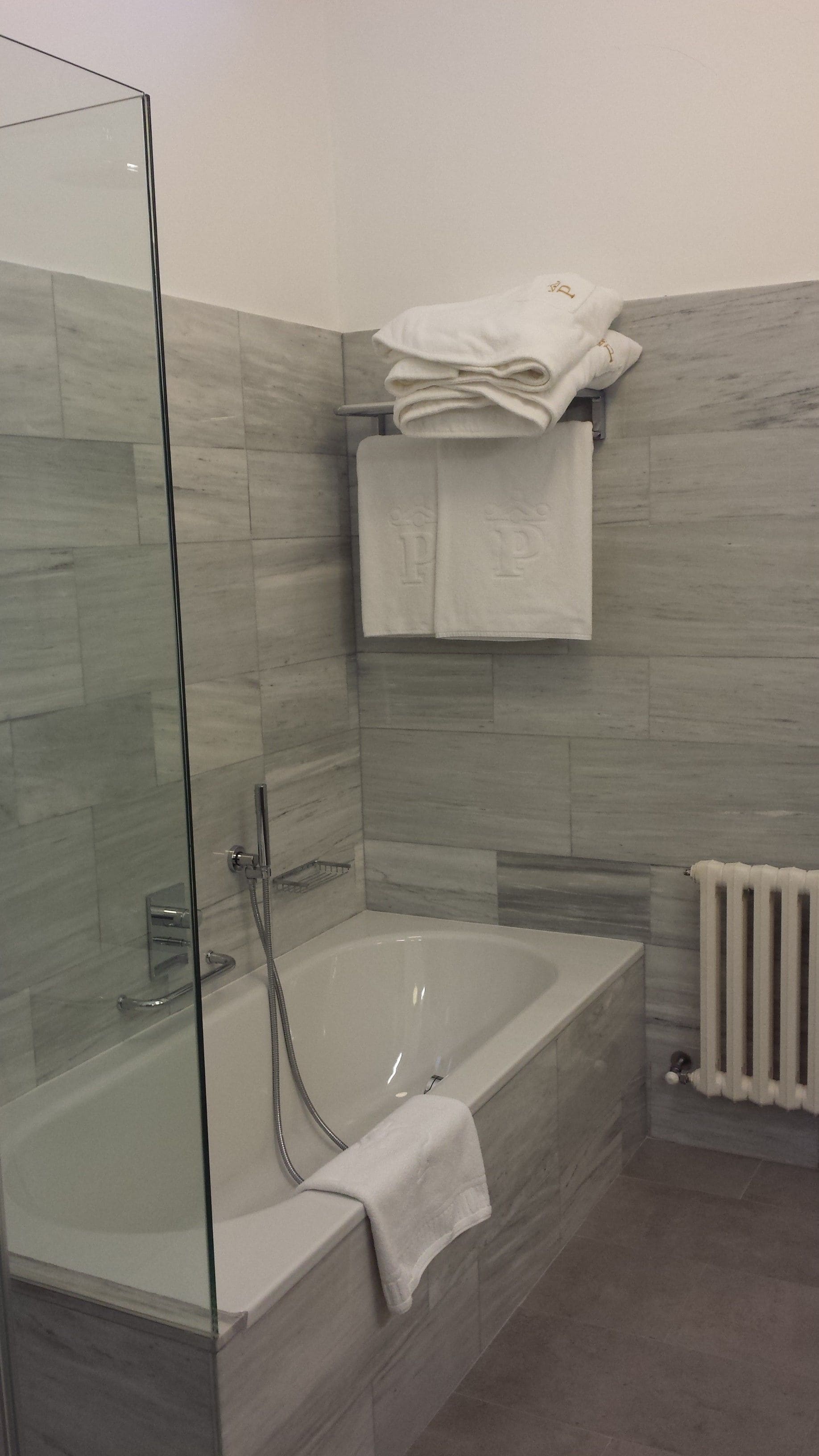 A modern bathroom with a glass-enclosed shower, a freestanding bathtub, and a towel rack with folded towels.