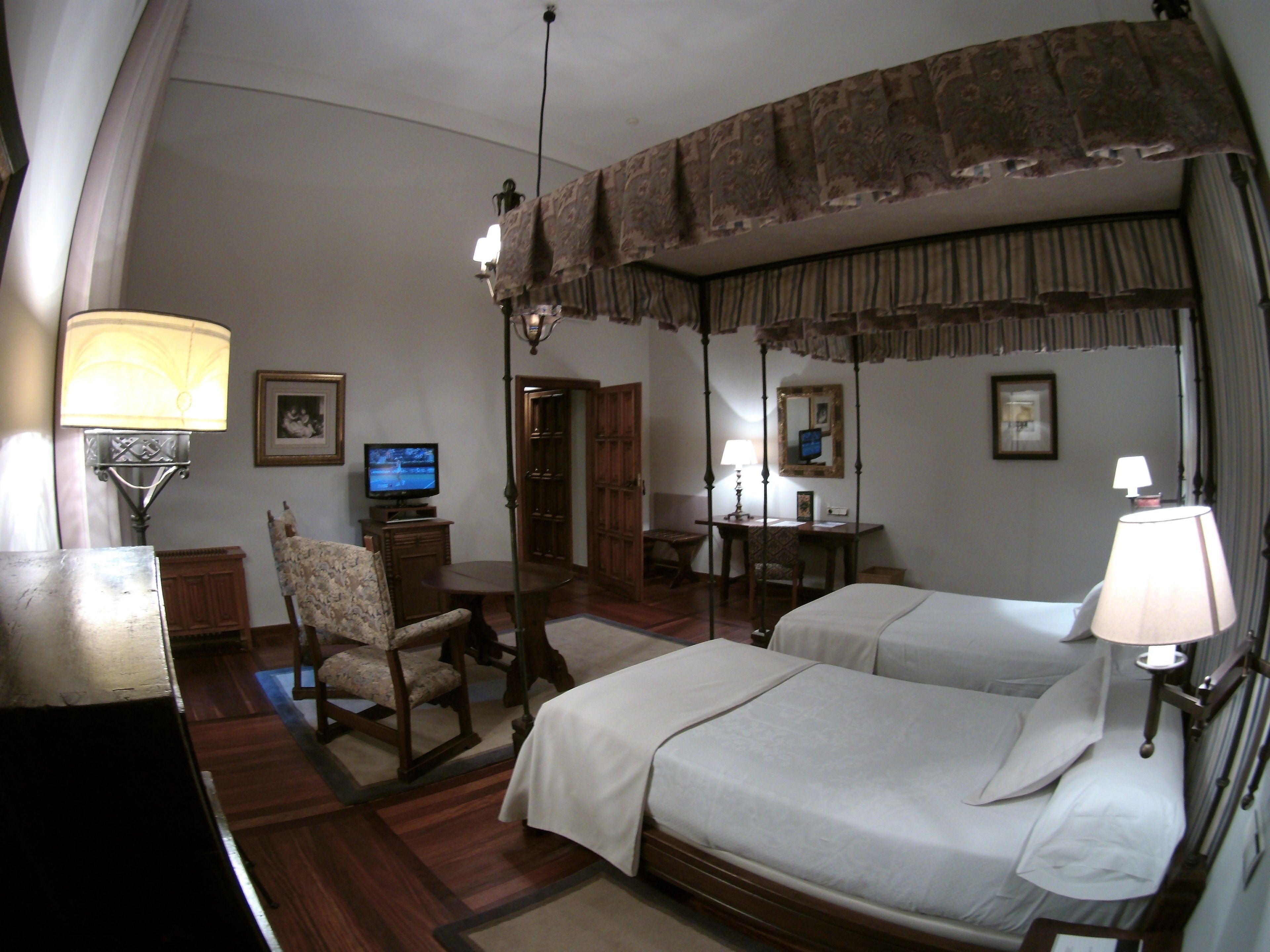 Una habitación de hotel con dos camas, un escritorio con silla, un televisor y una lámpara.