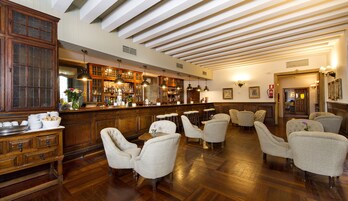 A bar area with wooden furniture, a bar counter, and a seating area with upholstered chairs.