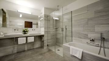 Une salle de bain moderne dotée d’une douche à parois de verre, d’une grande baignoire et d’un meuble-lavabo avec deux vasques.