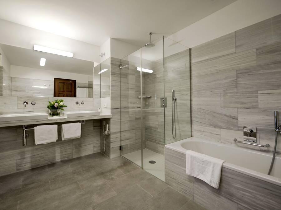 Une salle de bain moderne dotée d’une douche à parois de verre, d’une grande baignoire et d’un meuble-lavabo avec deux vasques.