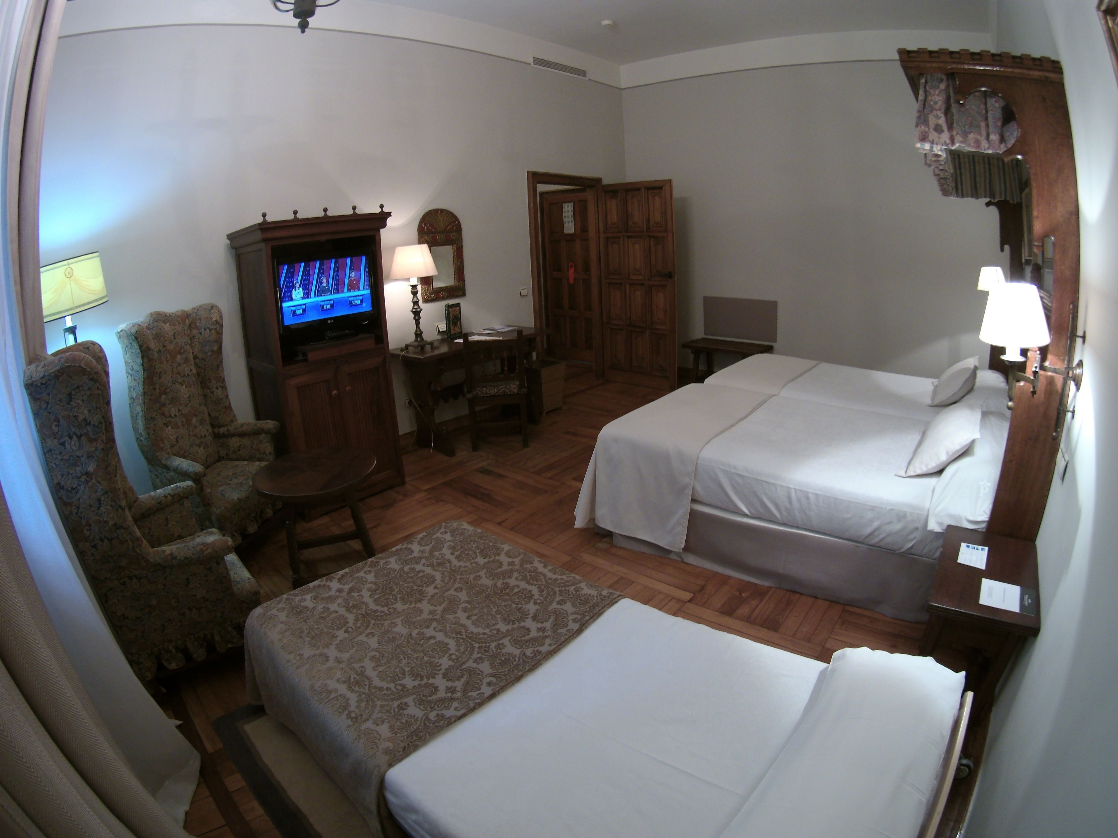A hotel room with two beds, a television, a desk, and a chair.
