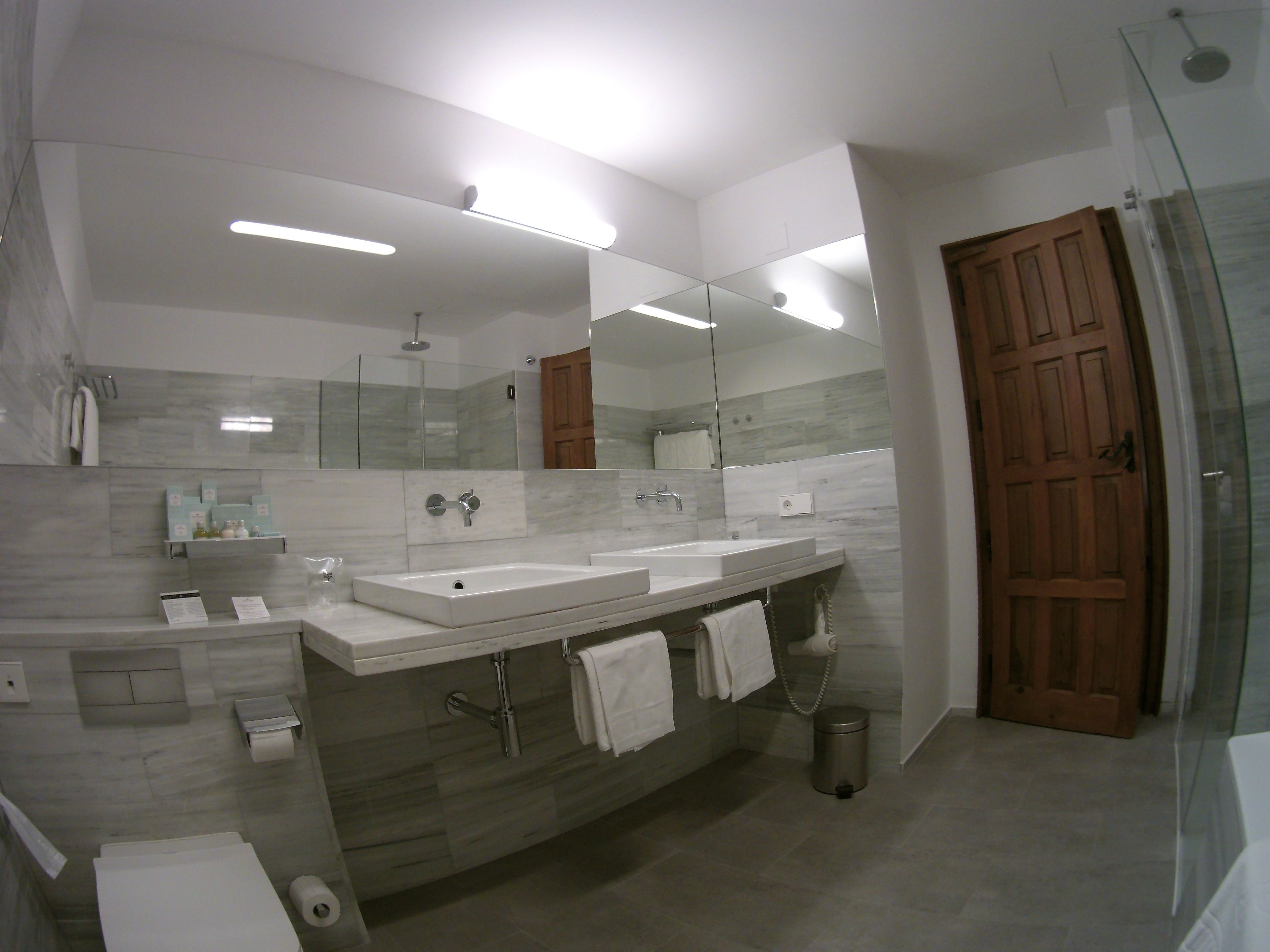 Un baño moderno con dos lavamanos, un espejo grande y una ducha.
