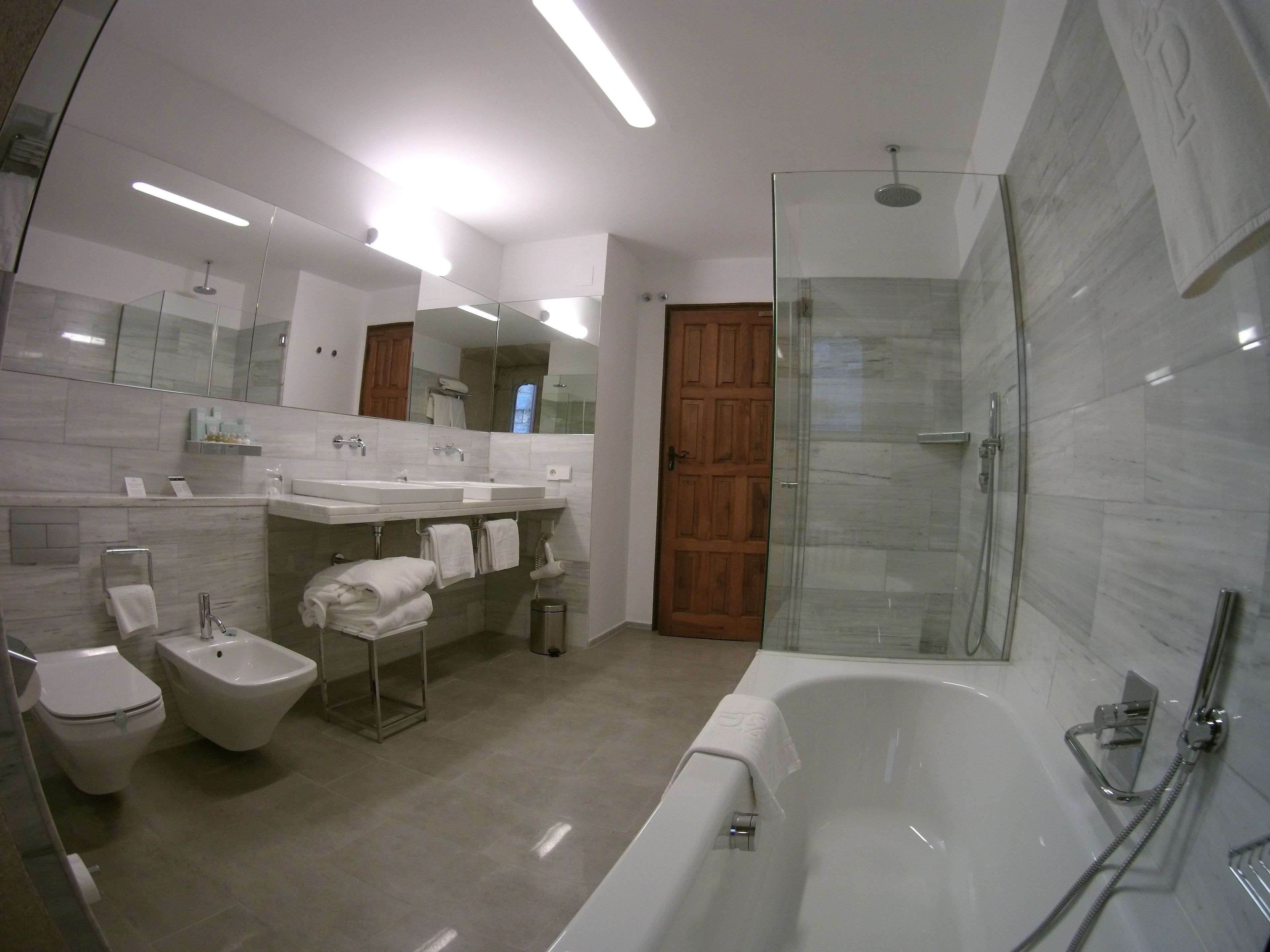 A modern bathroom with a bathtub, bidet, and glass-enclosed shower.