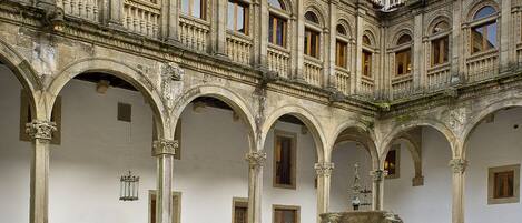Un patio con una fuente, arcos y un edificio con detalles ornamentales.