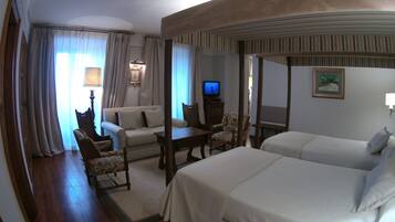 Una habitación de hotel con una cama grande, un sofá, un escritorio y un televisor.