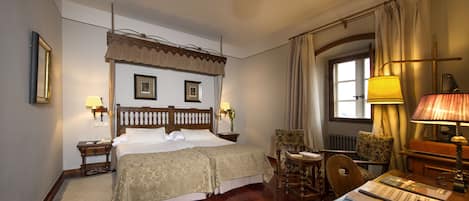 A hotel room with a large bed, a desk, a chair, a window, and a ceiling fan.