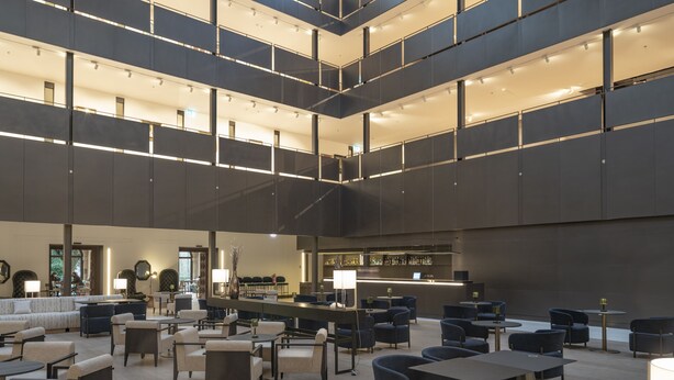 Um hall espaçoso com várias áreas de estar, um bar e uma escadaria que liga os andares.