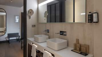 Une salle de bain moderne avec deux grands lavabos, un miroir et un banc.