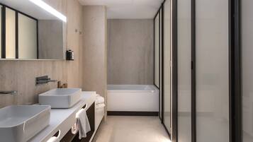 A modern bathroom with two sinks, a bathtub, and a large mirror.