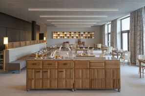Ein moderner Hotel-Speisesaal mit einer zentralen Insellösung, Sitzgelegenheiten und einer dekorativen Wand.