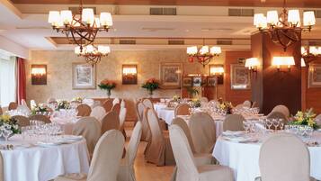 A banquet hall with multiple round tables set for dining, each with chairs and table settings.