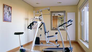 A gym with exercise equipment, a mirror, and a window with blinds.