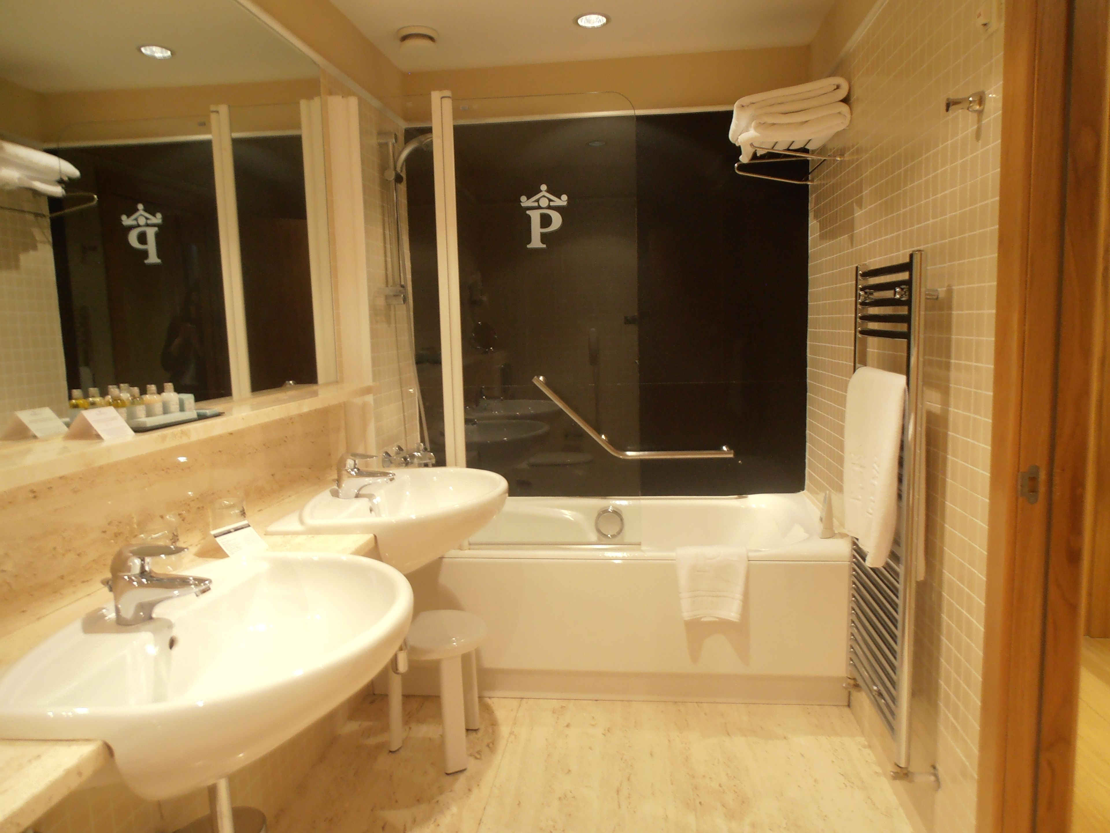 Un baño moderno con dos lavamanos, una bañera y una ducha.