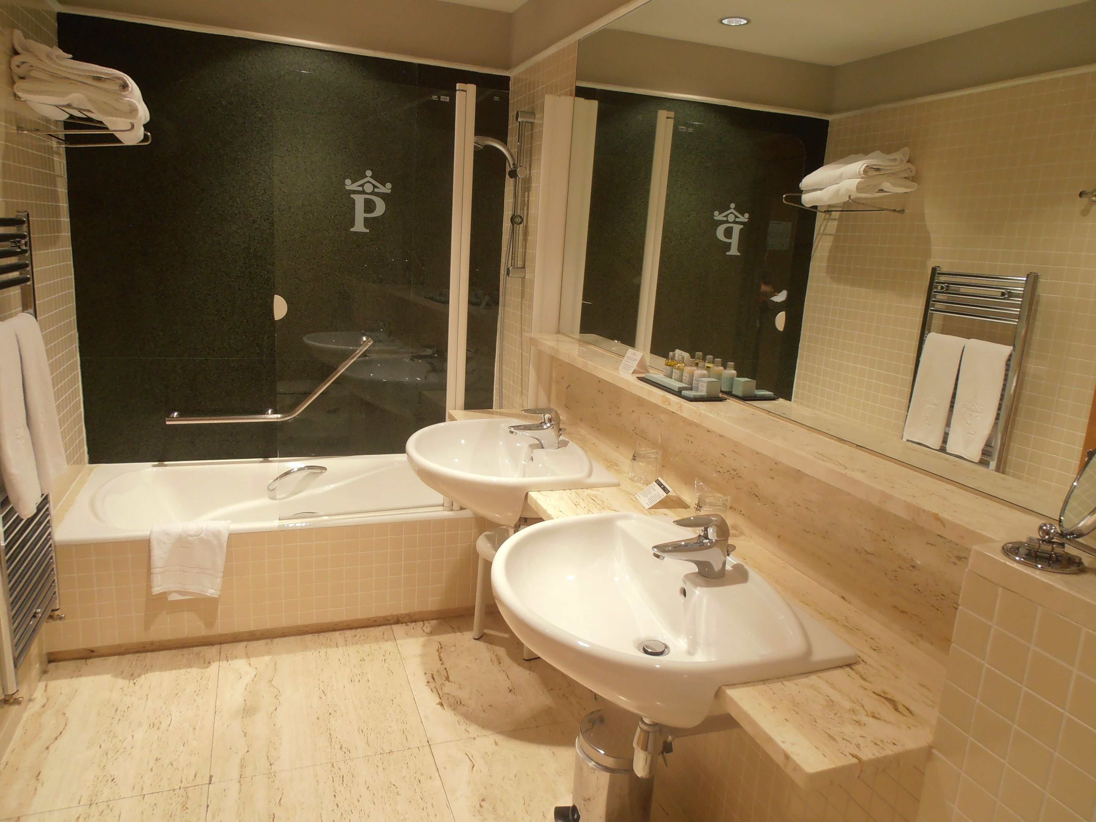 Un baño moderno con dos lavamanos, una bañera y una ducha.