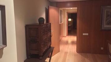 A hallway with wooden flooring and a wooden cabinet with a vase on top.