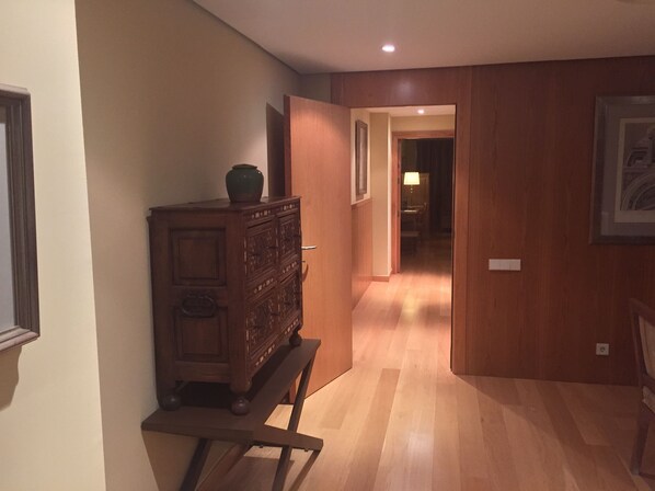 Un pasillo con suelo de madera y un mueble de madera con un jarrón encima.