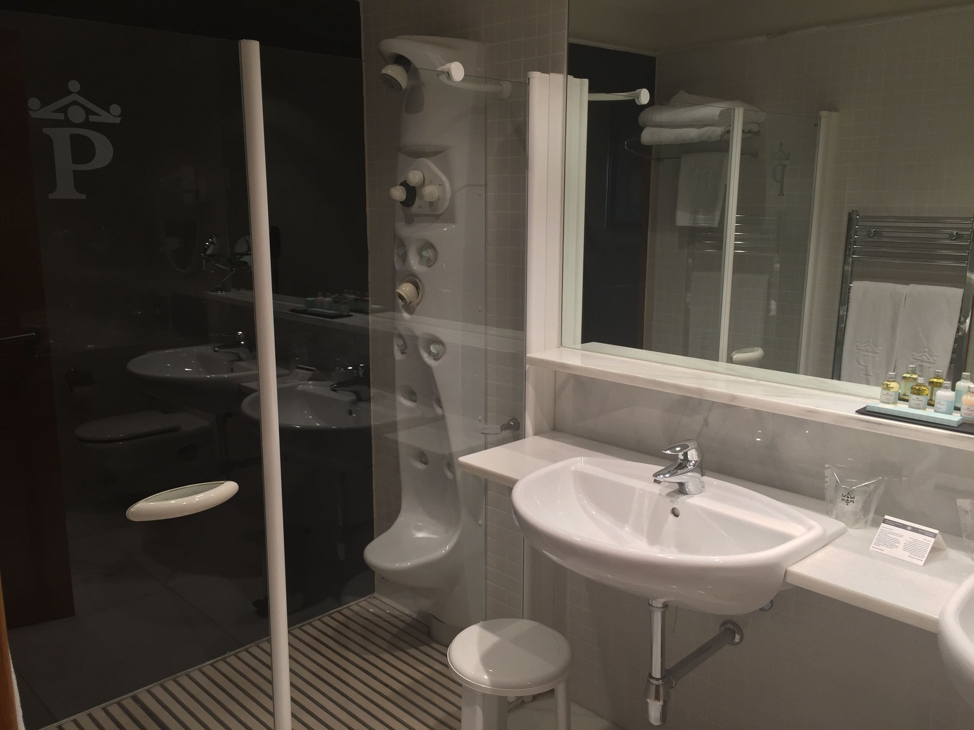 Un baño moderno con cabina de ducha de vidrio, un lavabo blanco y un espejo grande.