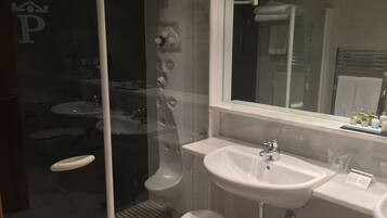 Un baño moderno con cabina de ducha de vidrio, un lavabo blanco y un espejo grande.