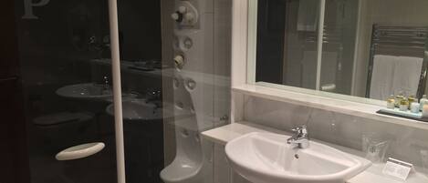 A modern bathroom with a glass shower enclosure, a white sink, and a large mirror.