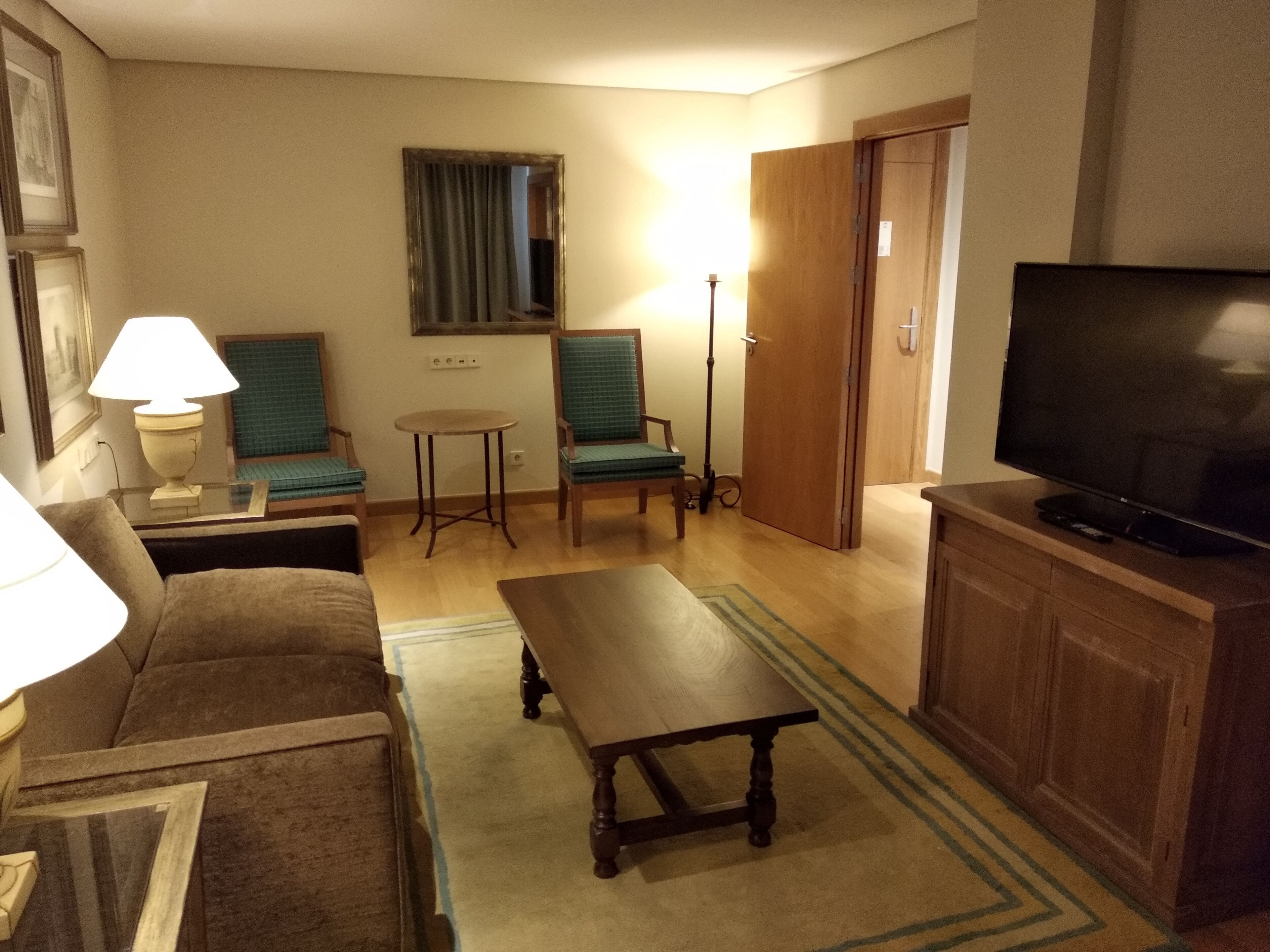 Un salon confortable avec un canapé, une table basse, un téléviseur et une lampe.