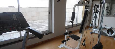 A gym with a treadmill, weight machines, and a mirror.