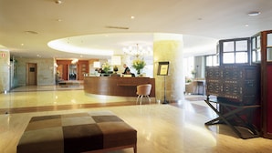 A spacious lobby with a reception desk, a seating area, and a large window providing natural light.
