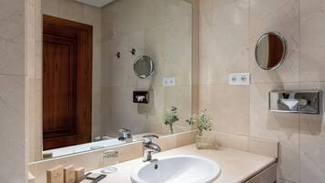 Un baño con lavabo, espejo y puerta de madera.